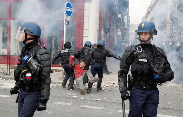 Kravallpoliser griper en ung demonstrant i Lyon.
