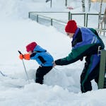 Förskolelärare Hans Persson stöttar. Alla barn har egna skidor som står och väntar.