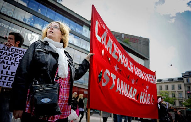 Elisabeth Ehn vid en av banderollerna på Sergels Torg. Anställda på Läkerols farbrik i Gävle, som ska flyttas till Slovakien, demonstrerade under torsdagen i Stockholm. Man marscherade från Sergels torg till Stureplan.
