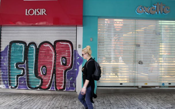 En fotgängare passerar en av alla stängda butiker i Athen på torsdagen.