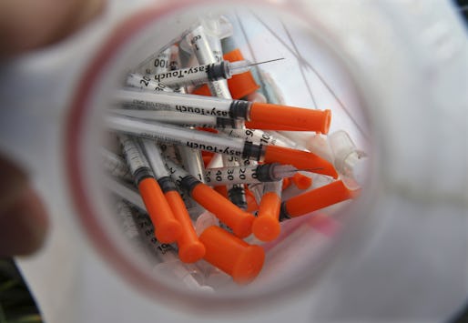 In this Thursday, Oct. 29, 2015 photograph, a jug of used needles to exchange for new is seen  near, Jim "Woods" Ellis in an industrial area of Camden, N.J., as Ellis describes using the drug, naloxone, often known by the brand name Nacran, to reverse an addict's heroin overdose. Naloxone works most of the time, but national statistics arenít kept on what happens to people who are revived. Some overdose again soon afterward. Some get treatment and get clean, but limited insurance, high costs and a shortage of spots at treatment centers can be hurdles. (AP Photo/Mel Evans)