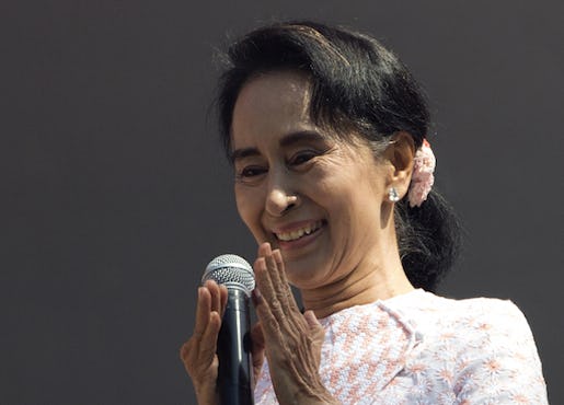 Leader of Myanmar's opposition National League for Democracy party, Aung San Suu Kyi, with ink still imprinted on the little finger of her left hand after voting Sunday, delivers a speech from a balcony of the NLD headquarters in Yangon, Myanmar, Monday, Nov. 9, 2015. Suu Kyi on Monday hinted at a victory by her party in the country's historic elections, and urged supporters not to provoke their losing rivals who are backed by the military.(AP Photo/Mark Baker)