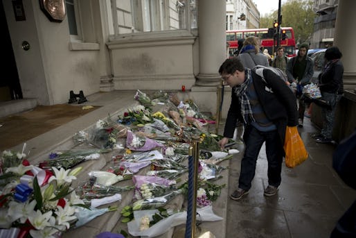 A man lays flowers for the victims of the deadly attacks in Paris, outside the French embassy in London, Saturday, Nov. 14, 2015. French President Francois Hollande said more than 120 people died Friday night in shootings at Paris cafes, suicide bombings near France's national stadium and a hostage-taking slaughter inside a concert hall. (AP Photo/Matt Dunham)