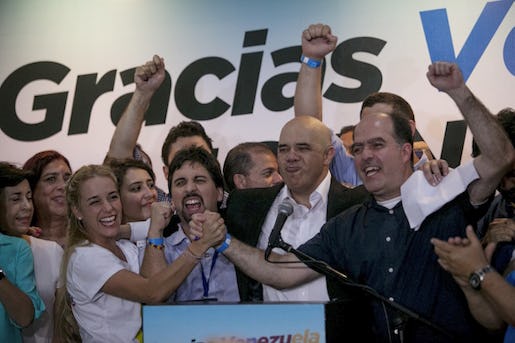 Opposition leaders, from left to right, Lilian Tintori, wife of jailed Venezuelan opposition leader Leopoldo Lopez, Freddy Guevara, of the Voluntad Popular party, Jesus Torrealba, head of the Democratic Unity Movement (MUD) party and deputy Julio Borges celebrate in Caracas, Venezuela, early Monday, Dec. 7, 2015. Venezuela's opposition won control of the National Assembly by a landslide on Sunday, delivering a major setback to the ruling party and altering the balance of power after 17 years of socialist rule.(AP Photo/Alejandro Cegarra)