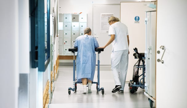 en sköterska och en patient går i sjukkorridor