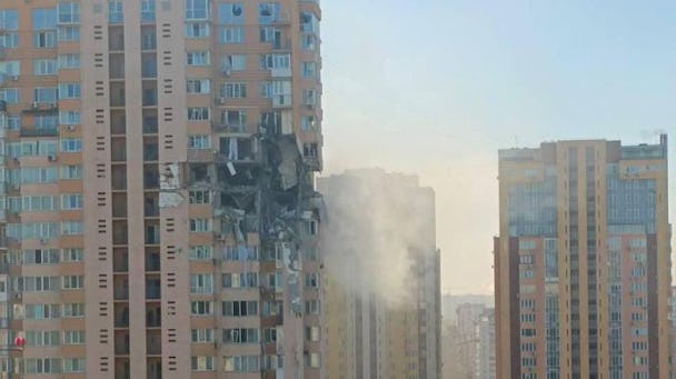 Fasaden på ett högt bostadshus har slitits upp av ryska bombningar. I bakgrunden syns flera liknande hus.