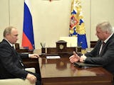 Rysslands president Vladimir Putin, till vänster, och den ryska fackliga federationen FNPR:s ordförande Mikhail Shmakov, till höger, konverserar över ett brunt träbord, sitter i vita fåtöljer, mot en vit vägg i bakgrunden hänger två ryska flaggor.
