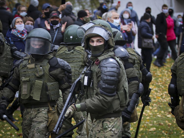 Militärklädda poliser skingrar en protest i Belarus huvudstad Minsk. I mitten av bilden står en polis med visiret uppfällt och ett gevär i händerna.