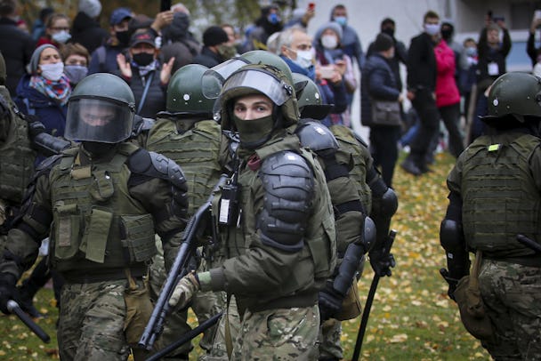 Militärklädda poliser skingrar en protest i Belarus huvudstad Minsk. I mitten av bilden står en polis med visiret uppfällt och ett gevär i händerna.