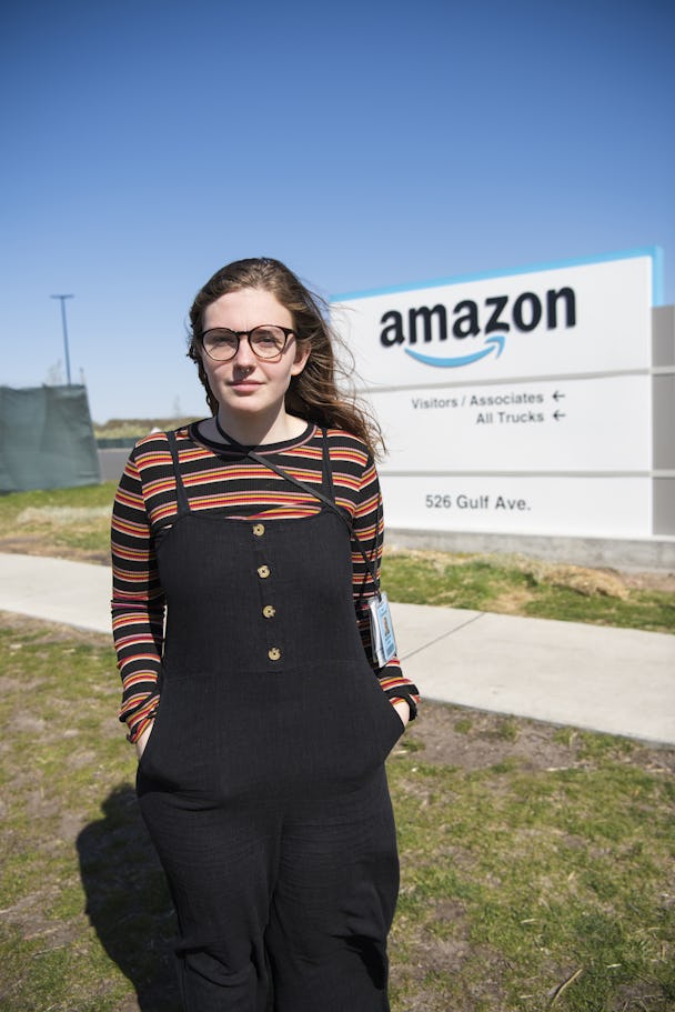 Madeline Wesley, i svarta hängselbyxor och randig tröja, står framför en skylt med Amazons logotyp.