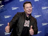 Teslachefen Elon Musk ler snett och gör tummen upp med bägge händerna, klädd i svart läderjacka.