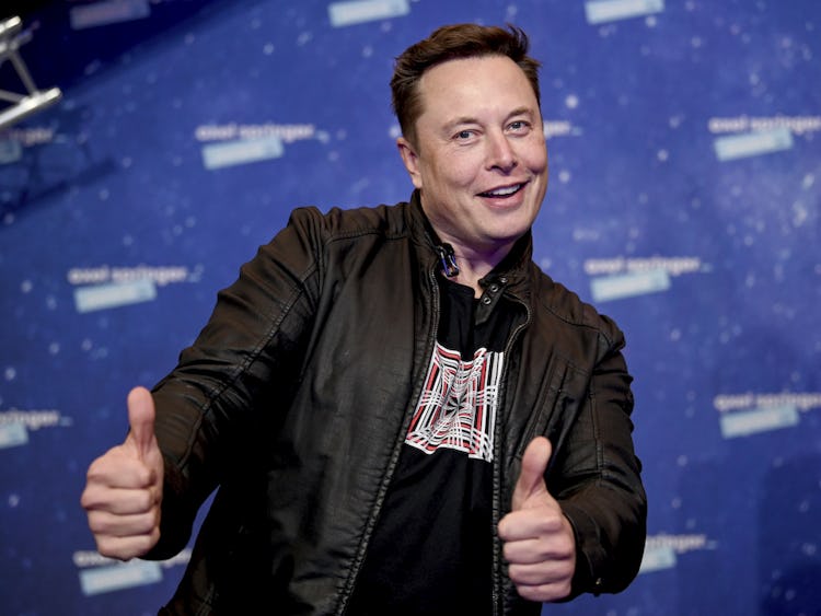 Teslachefen Elon Musk ler snett och gör tummen upp med bägge händerna, klädd i svart läderjacka.