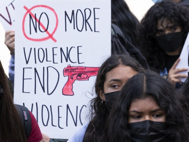 Kvinnliga skolelever med svarta ansiktsmasker i närbild runt ett plakat med texten: "Stoppa vapenvåldet."