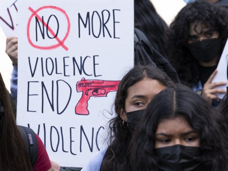 Kvinnliga skolelever med svarta ansiktsmasker i närbild runt ett plakat med texten: "Stoppa vapenvåldet."