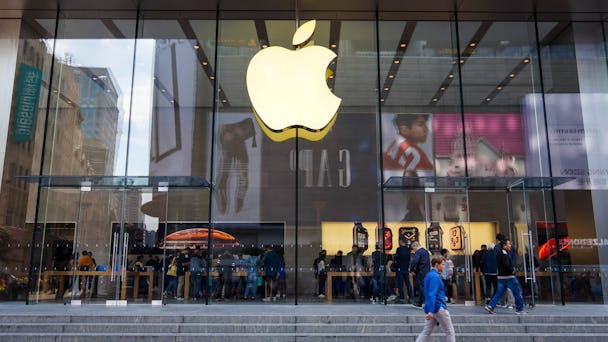 Apples logotyp syns på en glasfasad, bakom glaset tittar kunder på produkter.