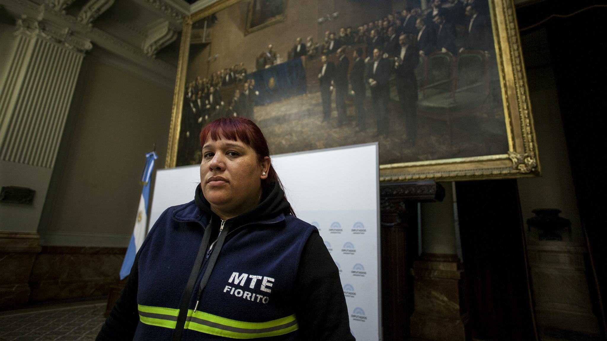 Natalia Zaracho, iklädd kommunal uniform, står framför en oljemålning i Argentinas parlament.