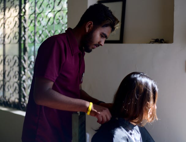 En man, fotograferad i profil, ger en kvinna en hårbehandling.