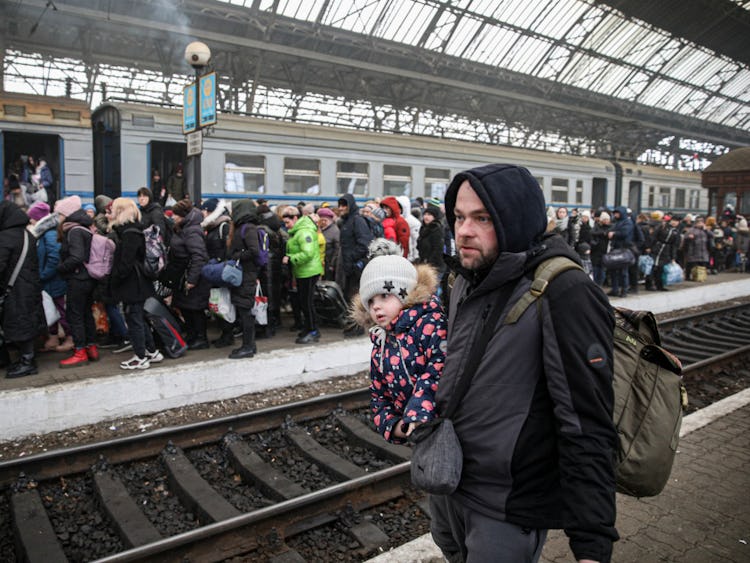 En ukrainsk man med en dotter i bärsele står på en tågperrong.