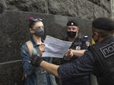 Ryska poliser, med ryggen mot kameran, griper en kvinna som håller en skylt i händerna.