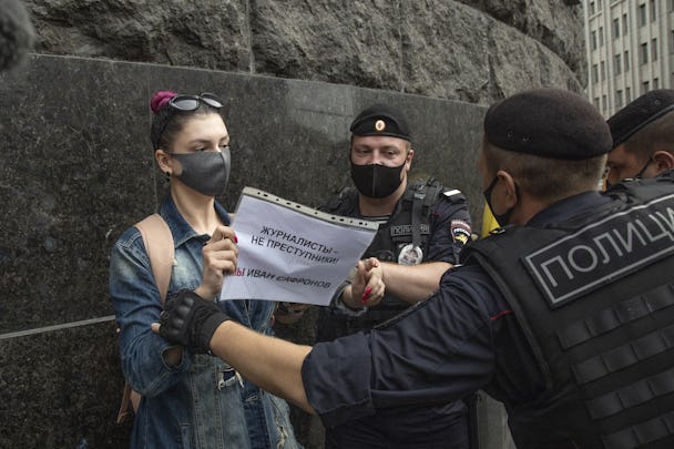 Ryska poliser, med ryggen mot kameran, griper en kvinna som håller en skylt i händerna.