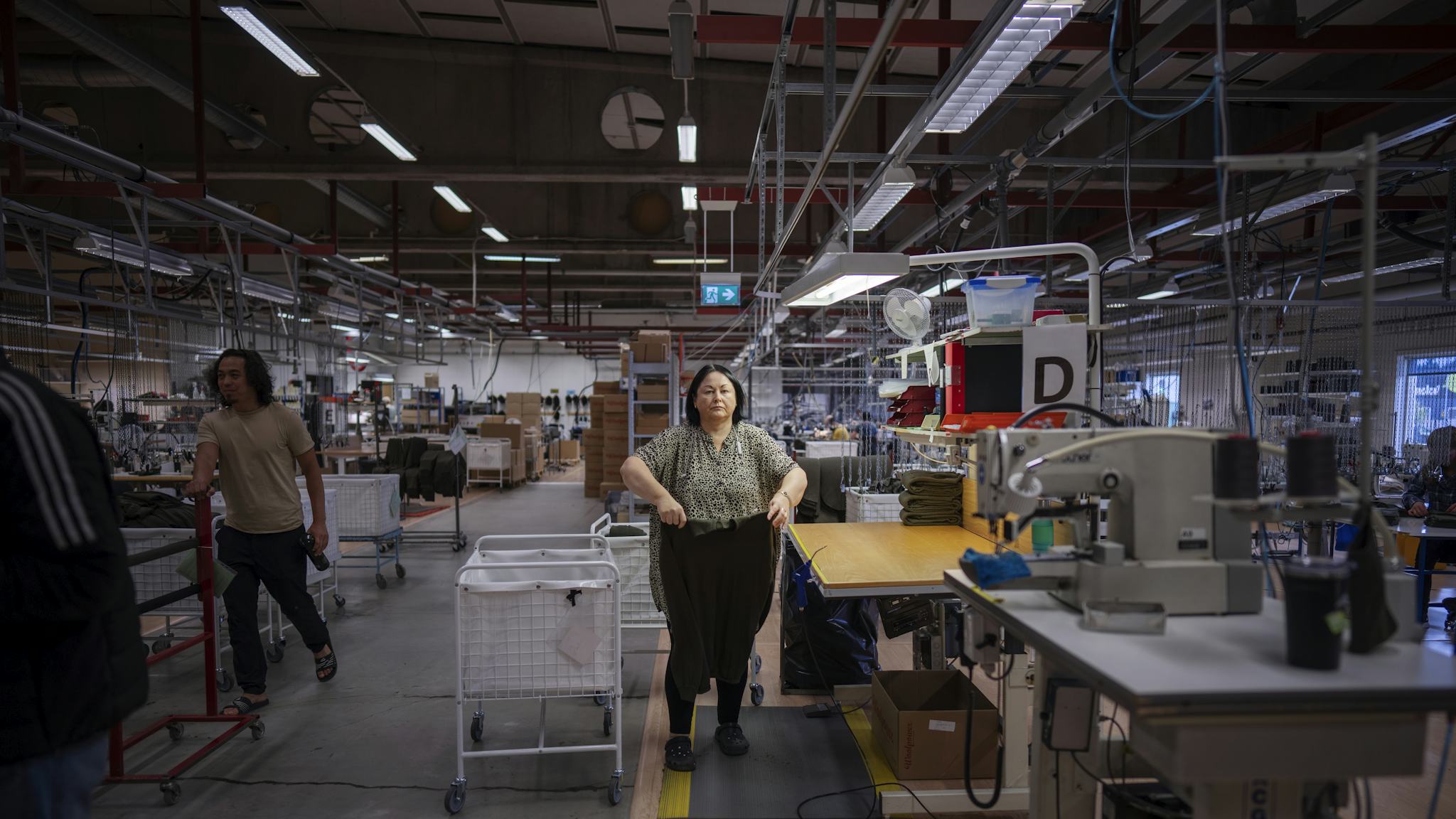 En kvinna viker kläder på ett fabriksgolv.
