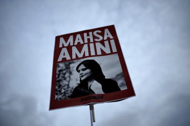 En skylt med porträtt på Mahsa Amini mot en molnig himmel.