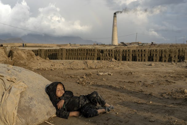 En liten flicka sover vid en tegelfabrik i Afghanistan, där barnarbetet ökat kraftigt efter talibanerna tog makten.