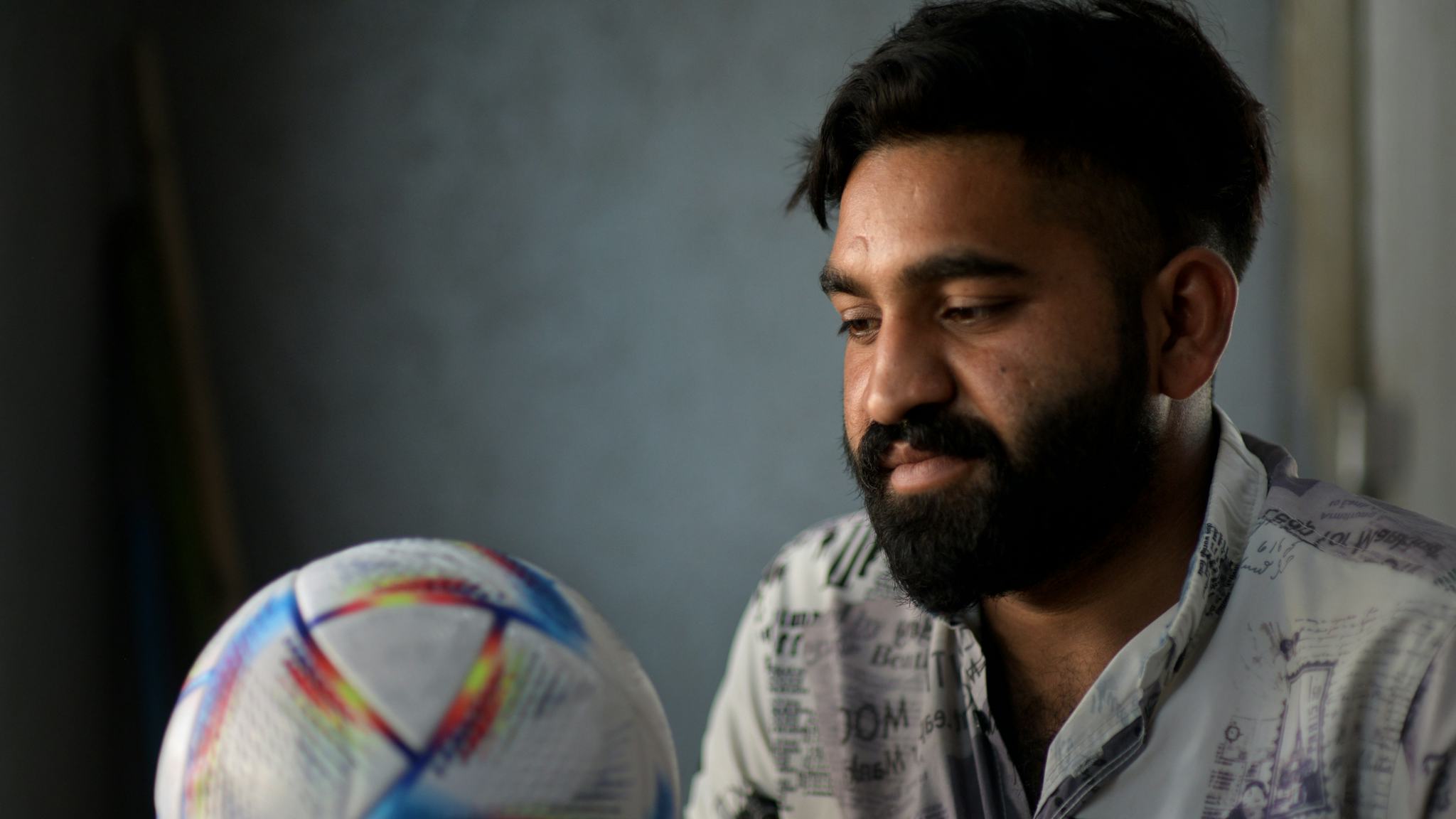 Bild på Ali Murtaza som tillverkar fotbollarna som ska användas under VM i Qatar. Han håller i en av VM-bollarna i handen.
