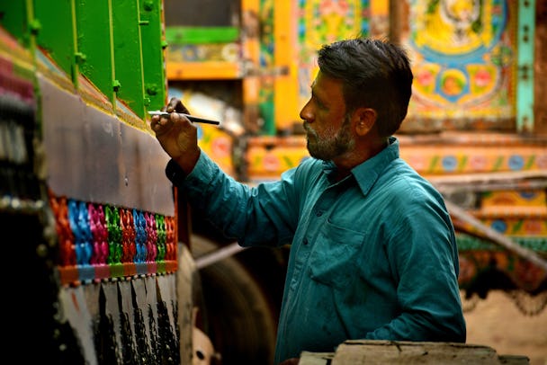 En målare dekorerar en lastbil i Pakistan