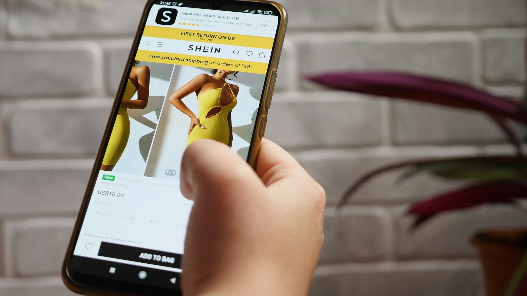 En hand håller en mobil som visar billiga kläder via Sheins app.