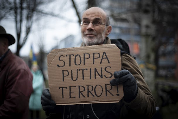 En man håller en skylt med texten "Stoppa Putins terror" på en manifestation för Ukraina.
