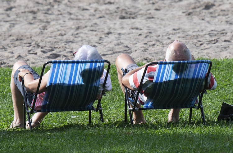 Ett äldre par njuter i sommarsolen i varsin solstol.