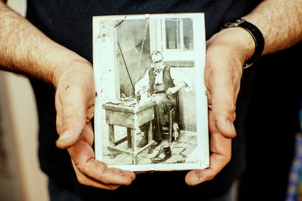 Skomakaren Joseph Aroyan håller upp ett gammalt foto.