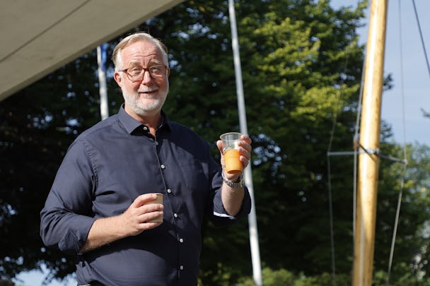Johan Pehrson håller ett glas apelsinjuice på en scen.