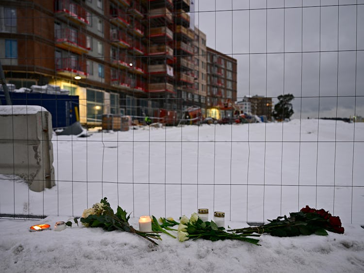 Blommor och ljus utanför byggarbetsplatsen där fem personer dog i en hissolycka.