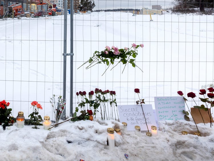 Blommor och ljus vid minnesplatsen för de som dog i hissolyckan.