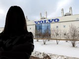 Siluetten av en kvinna som står framför en Volvofabrik.