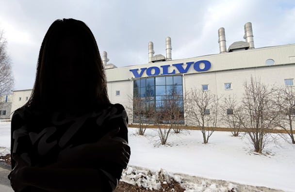 Siluetten av en kvinna som står framför en Volvofabrik.