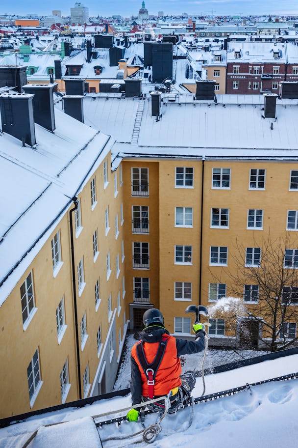 En man på ett snötäckt tak i stockholm, sverige.