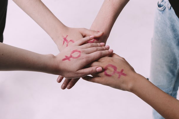 En grupp människor håller hand med en symbol målad på dem.