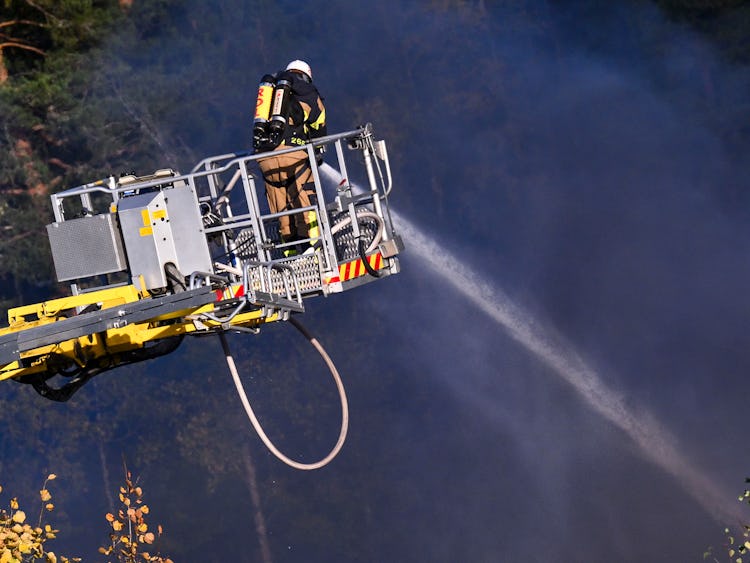 En brandman sprutar vatten från en brandbil.