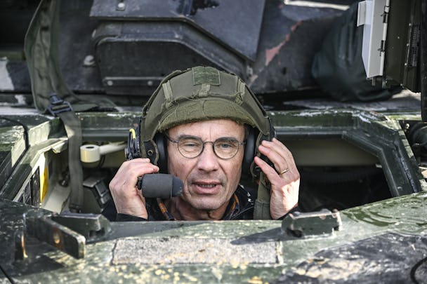 En man i hjälm pratar i telefon i ett militärfordon.