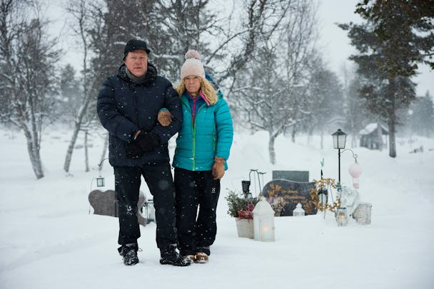 En man och kvinna som står i snön framför en kyrkogård.