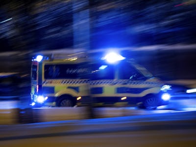En ambulans kör nerför en gata på natten.