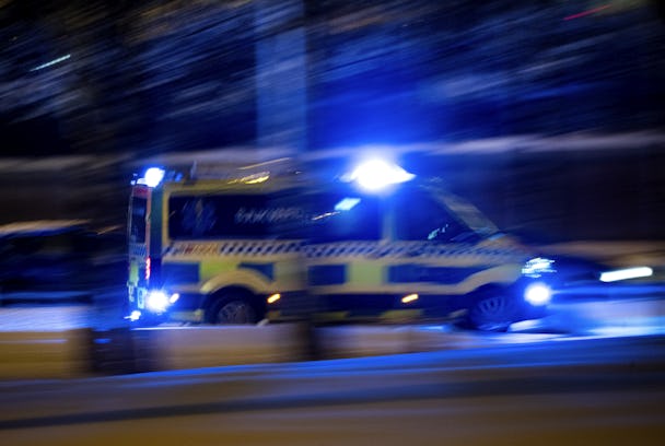 En ambulans kör nerför en gata på natten.