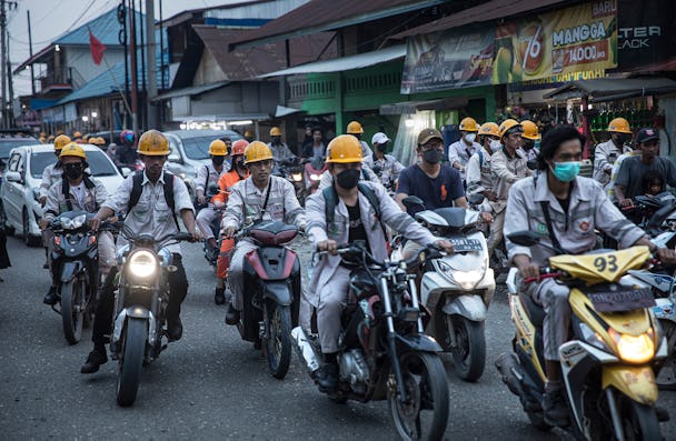 Arbetare i Indonesien på mopeder.