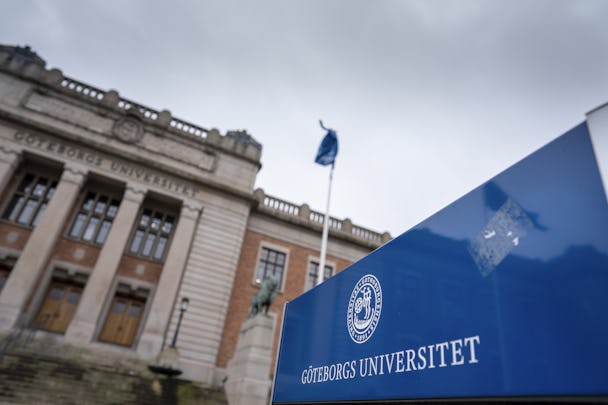 Skylt som visar Göteborgs universitets logotyp i förgrunden, med den historiska universitetsbyggnaden något oskarp i bakgrunden.
