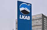 En hög skylt med LKAB-logotypen står framför en flervånings kontorsbyggnad under en grå himmel.