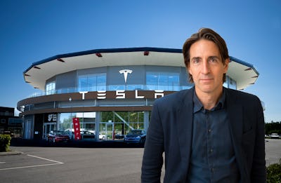 En man i kostym står framför en Tesla-återförsäljningsbyggnad.