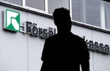 Silhuett av en person framför en byggnad med texten "Försäkringskassan" och en grön symbol, som indikerar Sveriges socialförsäkringsmyndighet.